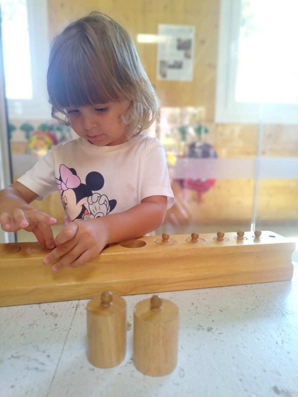 Bambino gioca con un asta di legno e cilindri su un tavolo