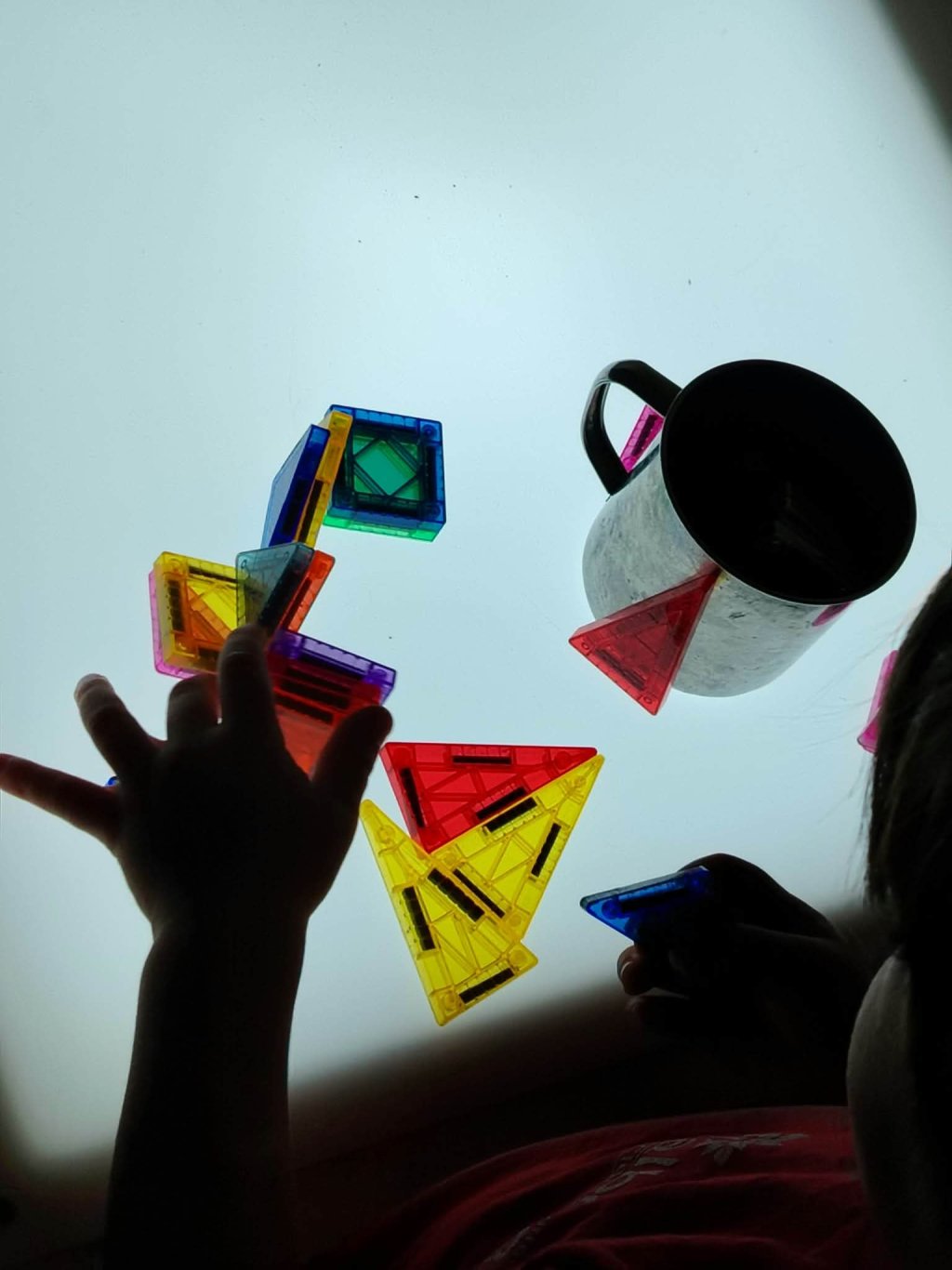 Mani di bambini che giocano con blocchi colorati su una superficie trasparente