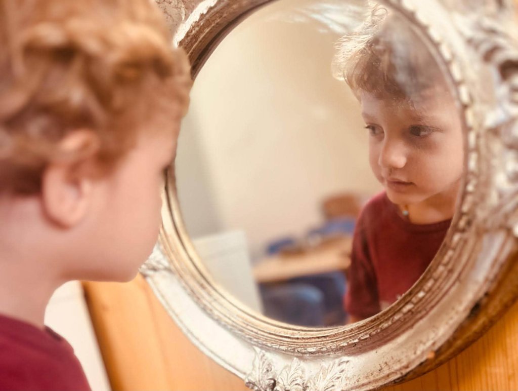 Bambino si guarda nello specchio con cornice d'argento