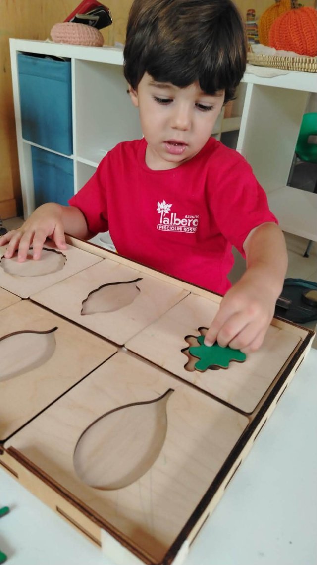 Bambino gioca con un puzzle di legno su un tavolo