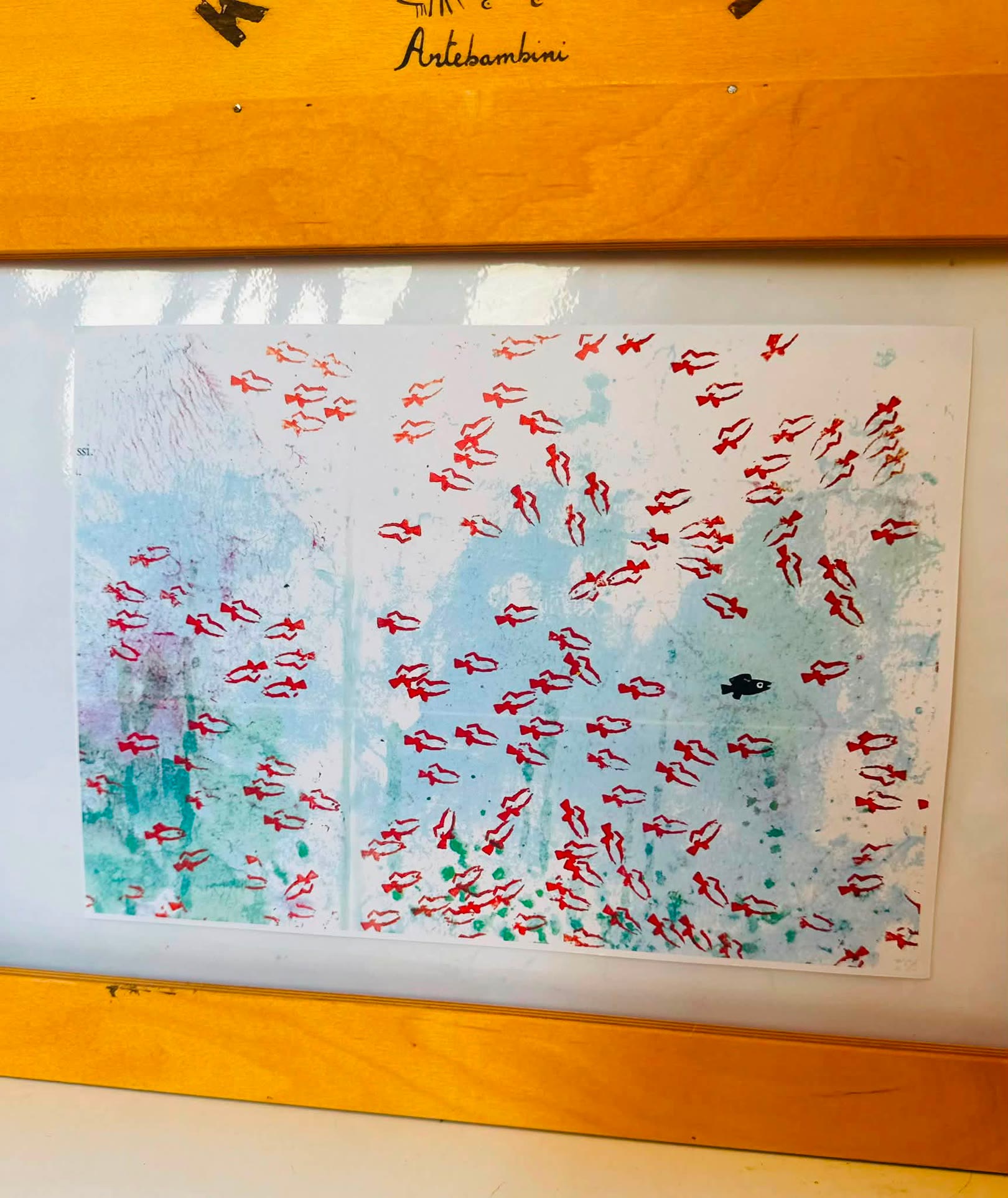 Pittura su carta con impronte rosse su sfondo blu, appesa su bacheca gialla