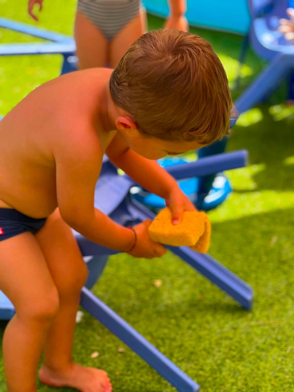 Un bambino si lava le mani con una spugna in un parco giochi
