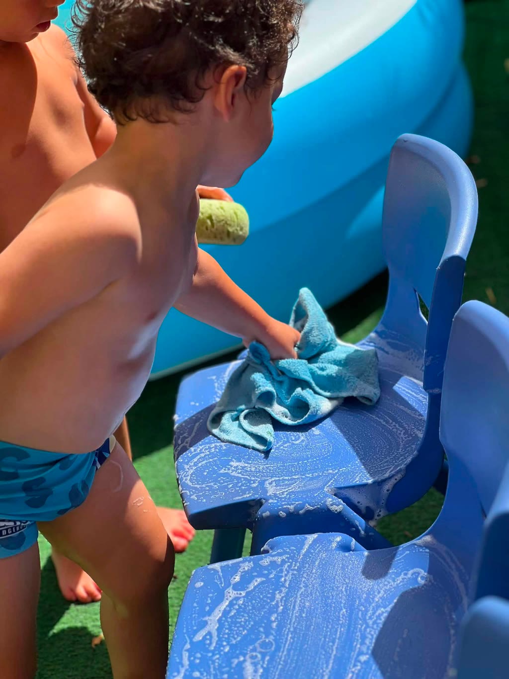 Due bambini stanno pulendo sedie blu con spugna e asciugamano