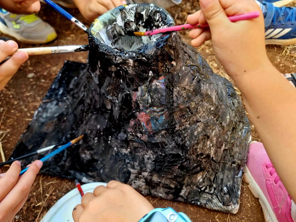 Bambini stanno dipingendo un sacchetto di plastica con pennelli colorati