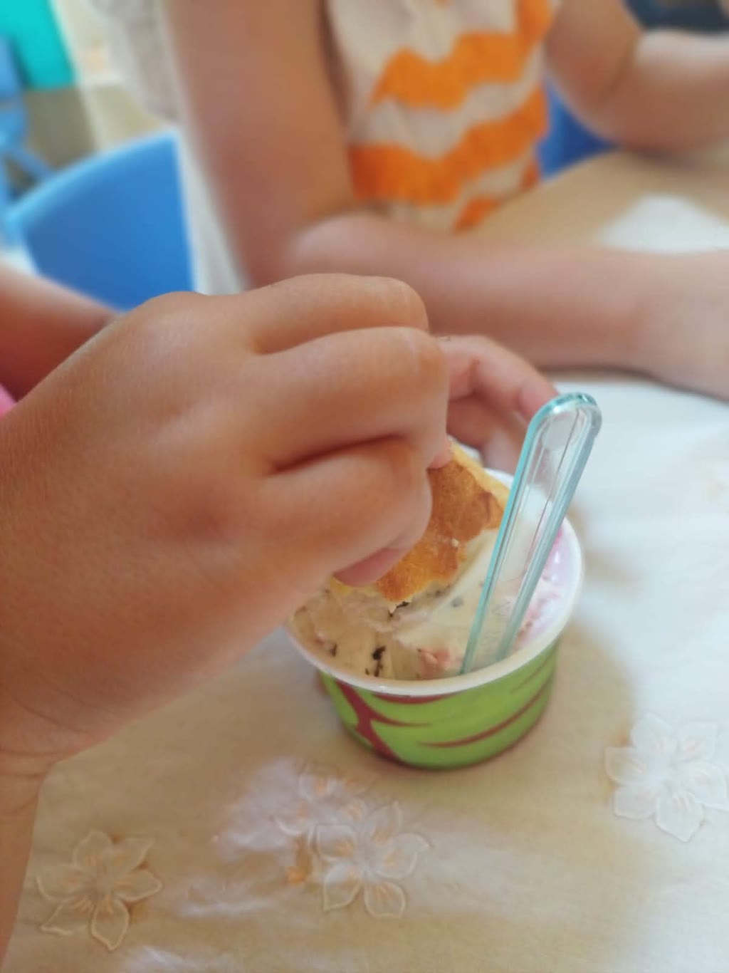Mani di bambino che mangiano gelato con una cialda