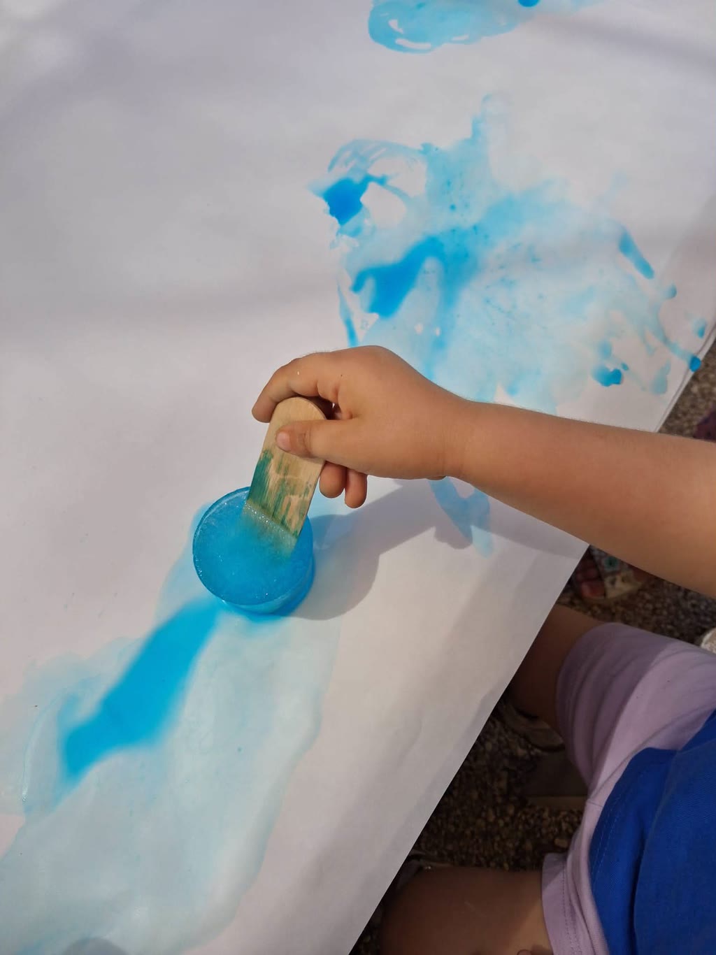 Mano con pennello che dipinge su carta con colori blu
