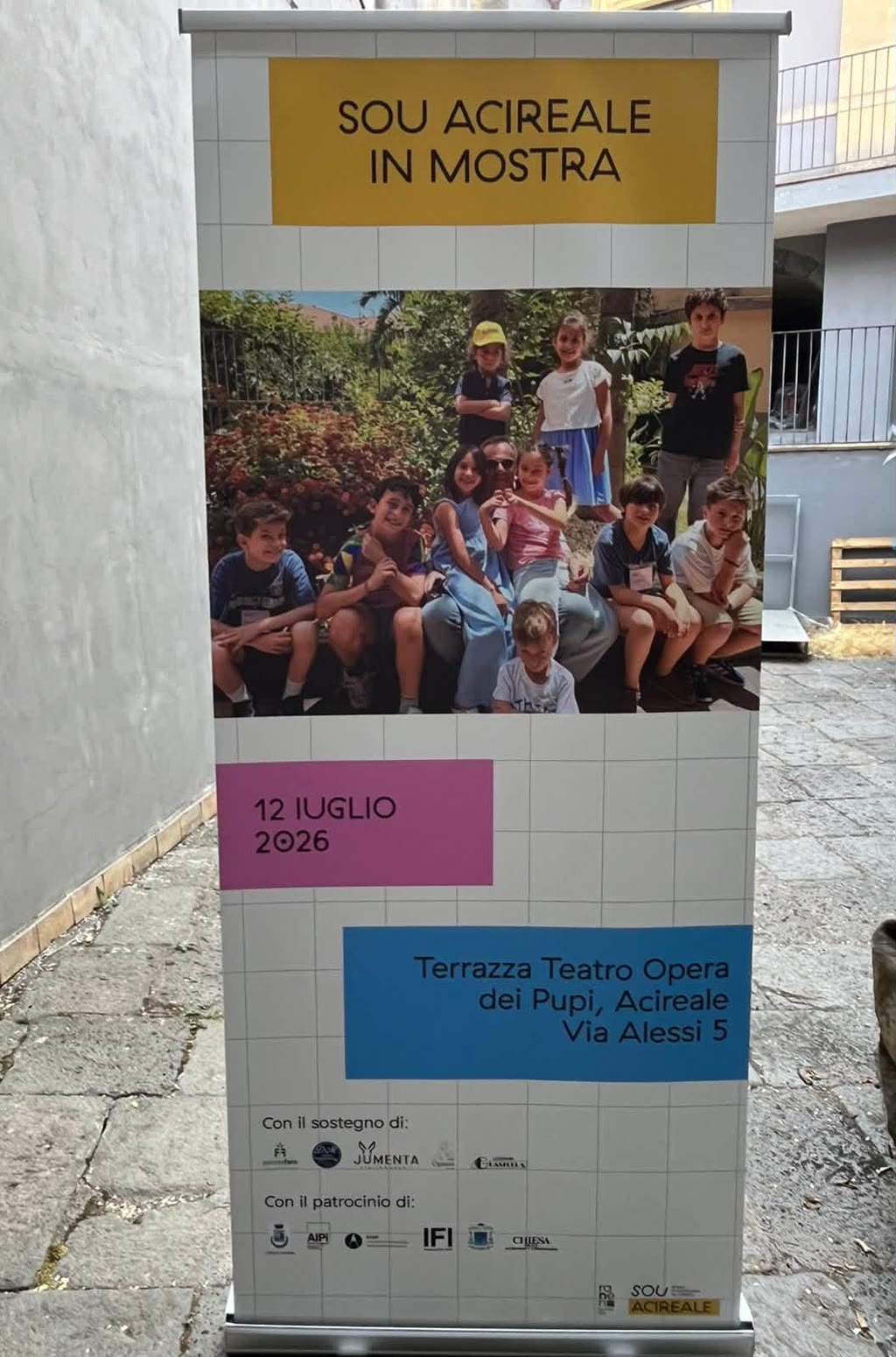 Un manifesto annuncia SOU ACIREALE IN MOSTRA con data, luogo e benefattori