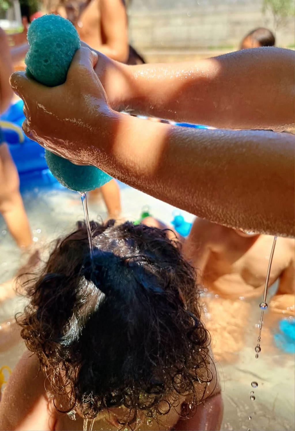 Mani lavano i capelli con una spugna blu in piscina