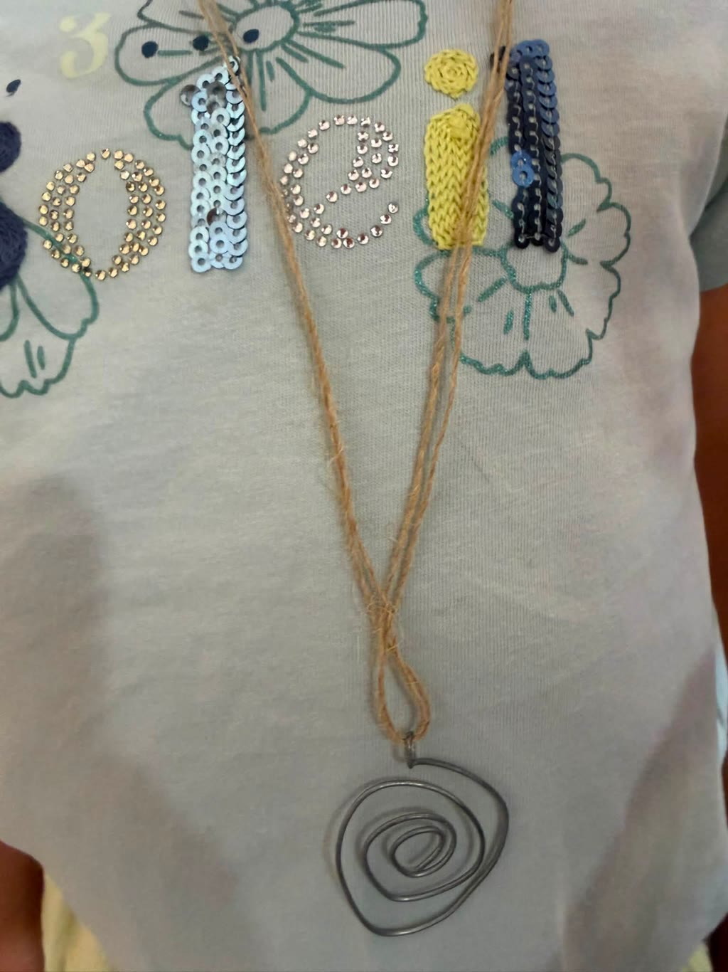 Una maglietta con scritta 3 opere e un pendente a spirale