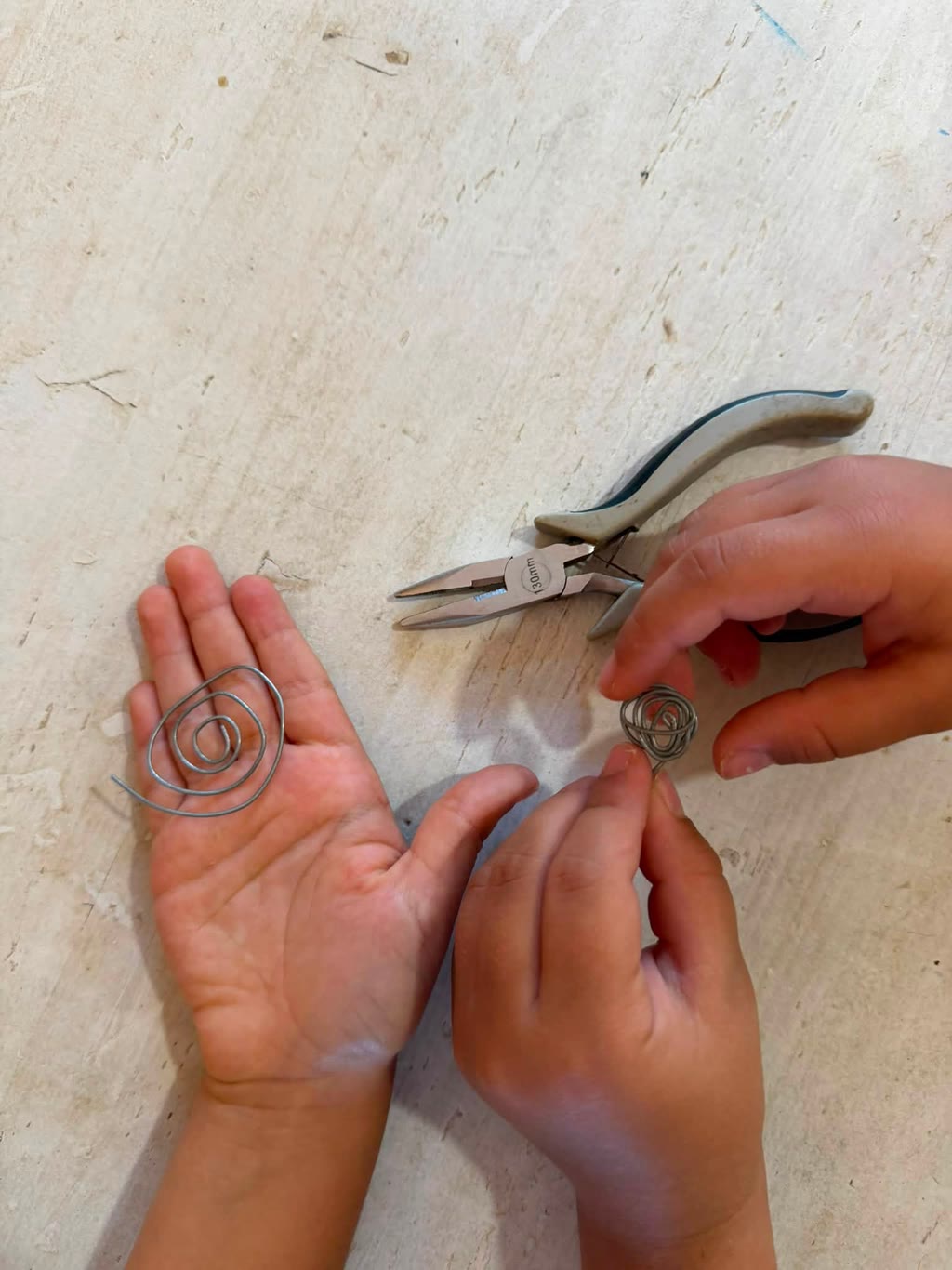 Due mani tengono anelli di filo, una con forbici sul tavolo
