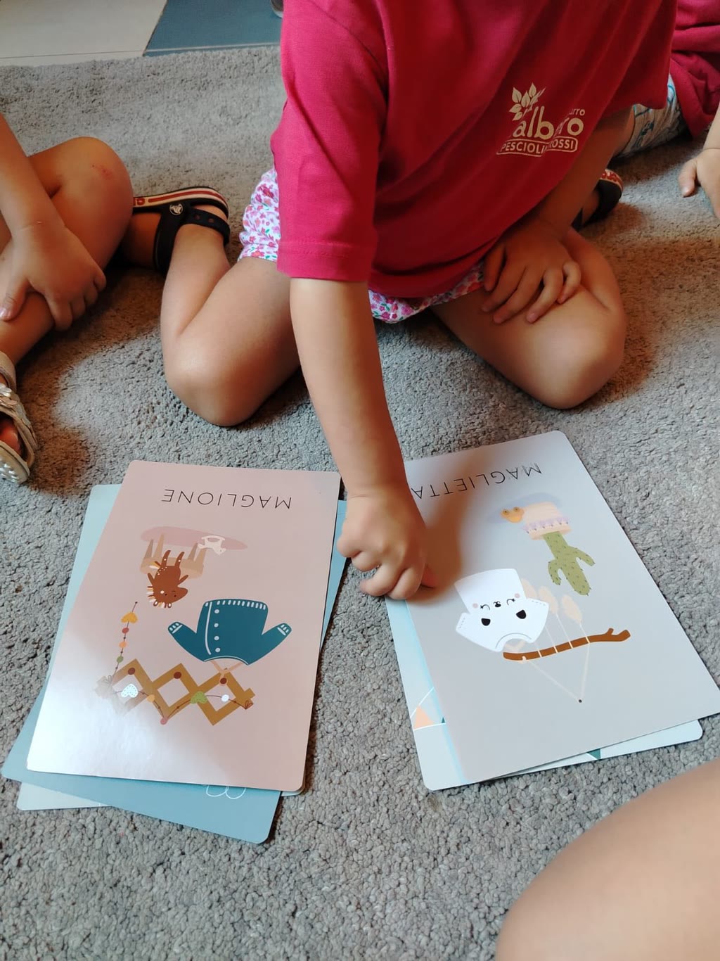 Due bambini giocano con carte illustrate sul tappeto