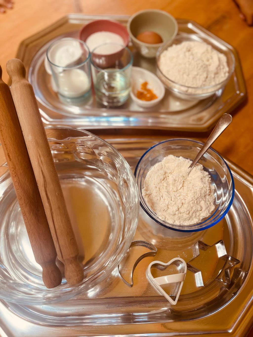 Una tavola trasparente con ingredienti per la pasta da impastare, un mattarello, e forme da biscotti