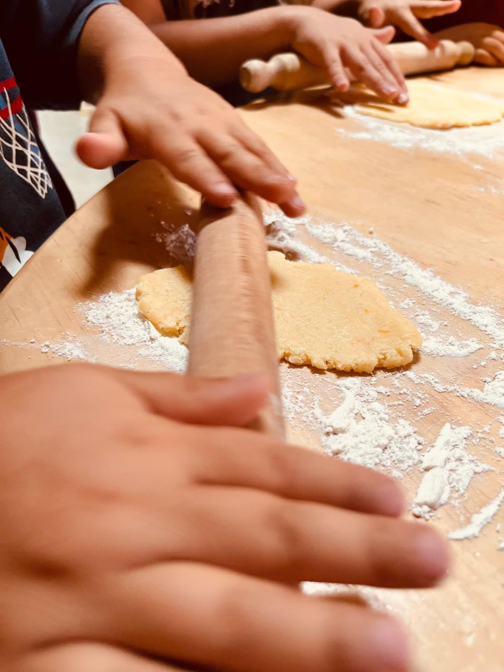 Mani che impastano e stendono pasta su un tavolo coperto di farina