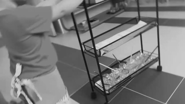 Una persona si appoggia a un tavolo con un carrello contenente bicchieri e posate