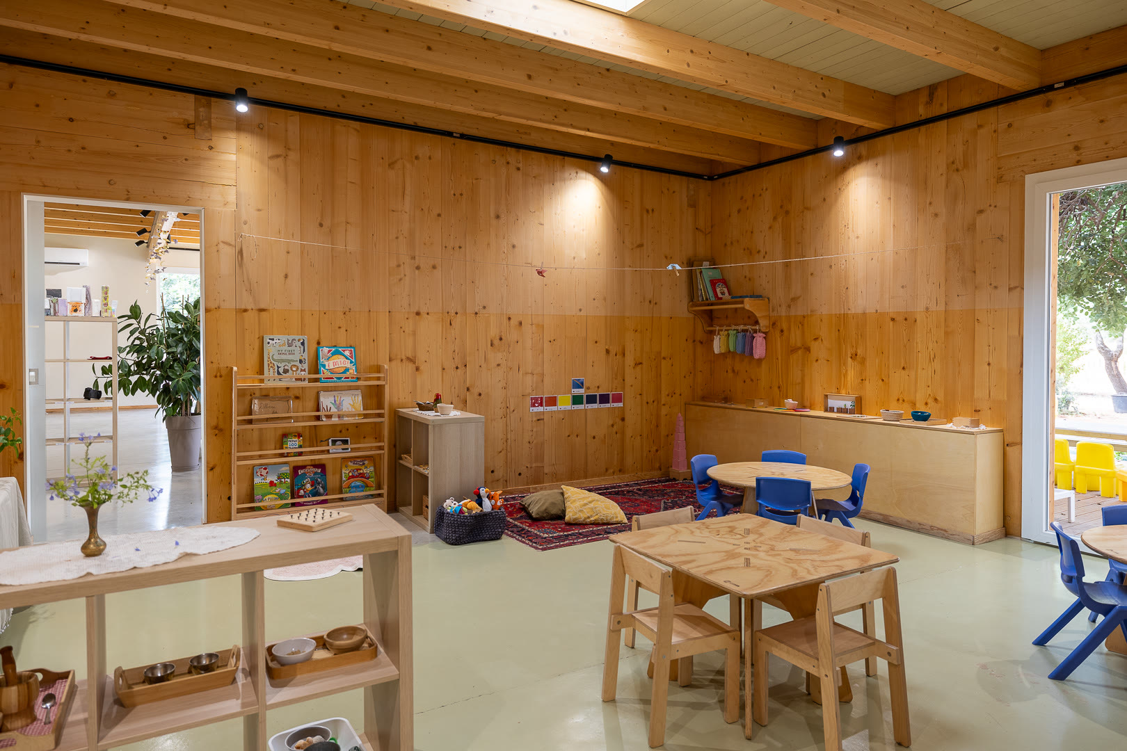 Ambiente rivestito in legno con gli scaffali dei materiali e il tappeto di lavoro.