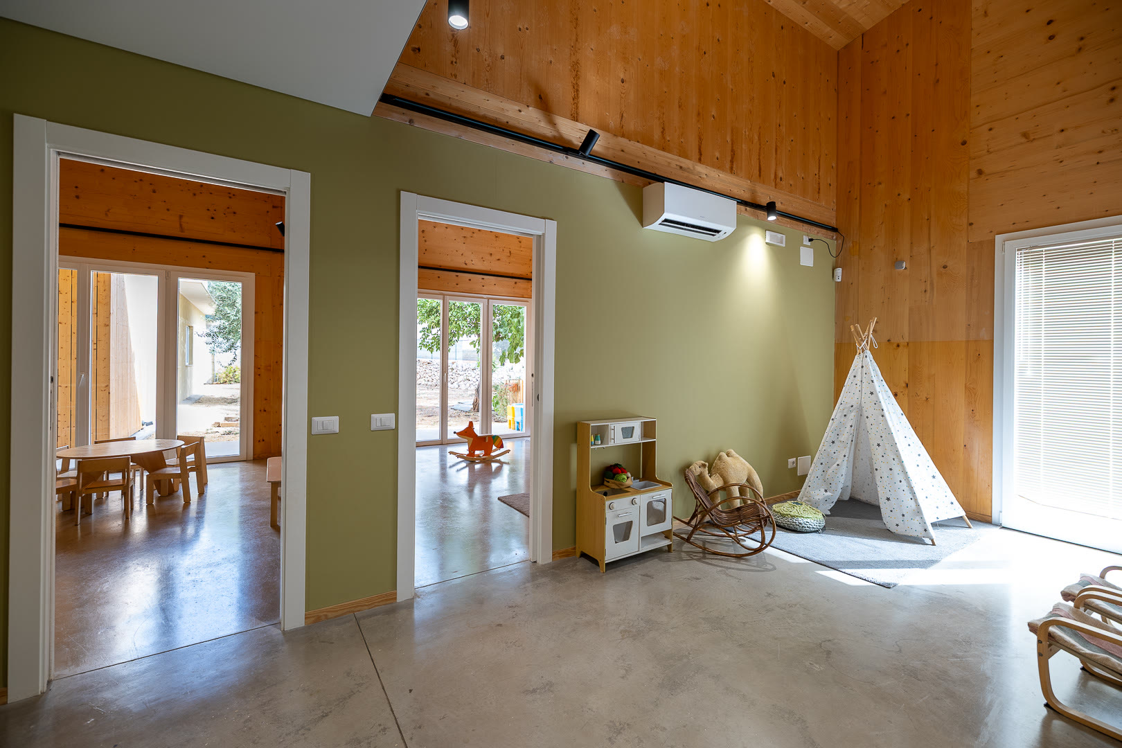 Tenda di tela bianca a forma di tepee nell'angolo di una stanza dalla parete verde.