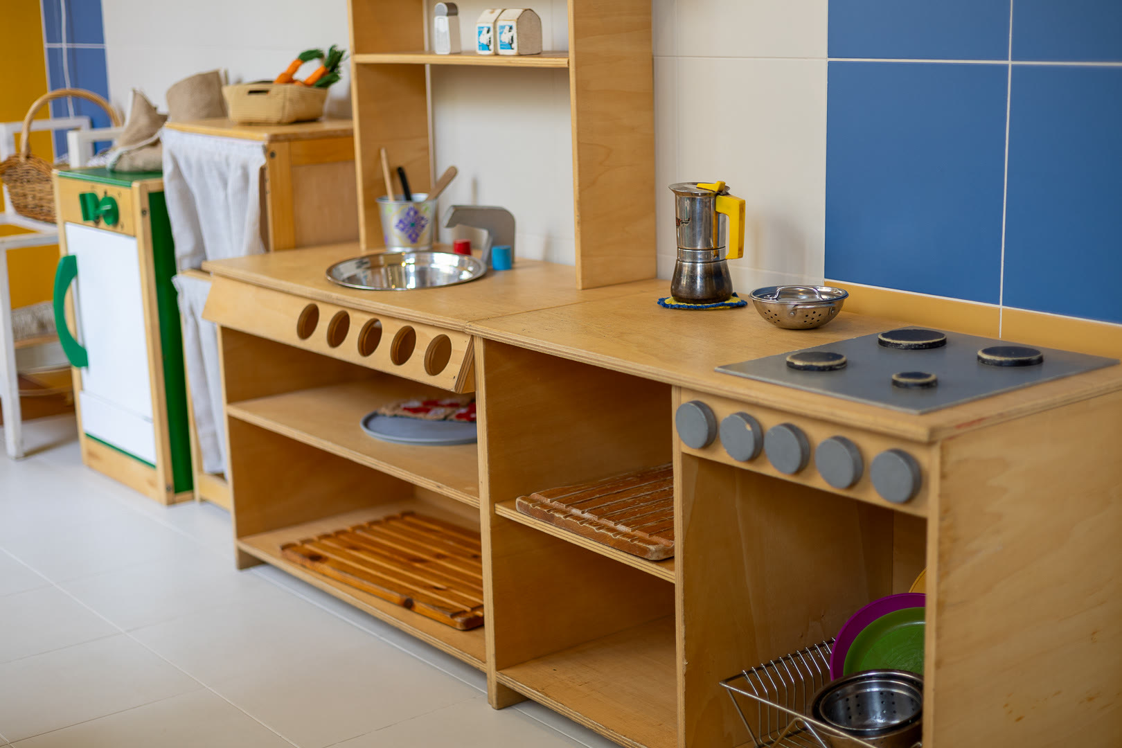 La cucina in legno per il gioco, con le pentole vere e le stoviglie a portata di bambino.