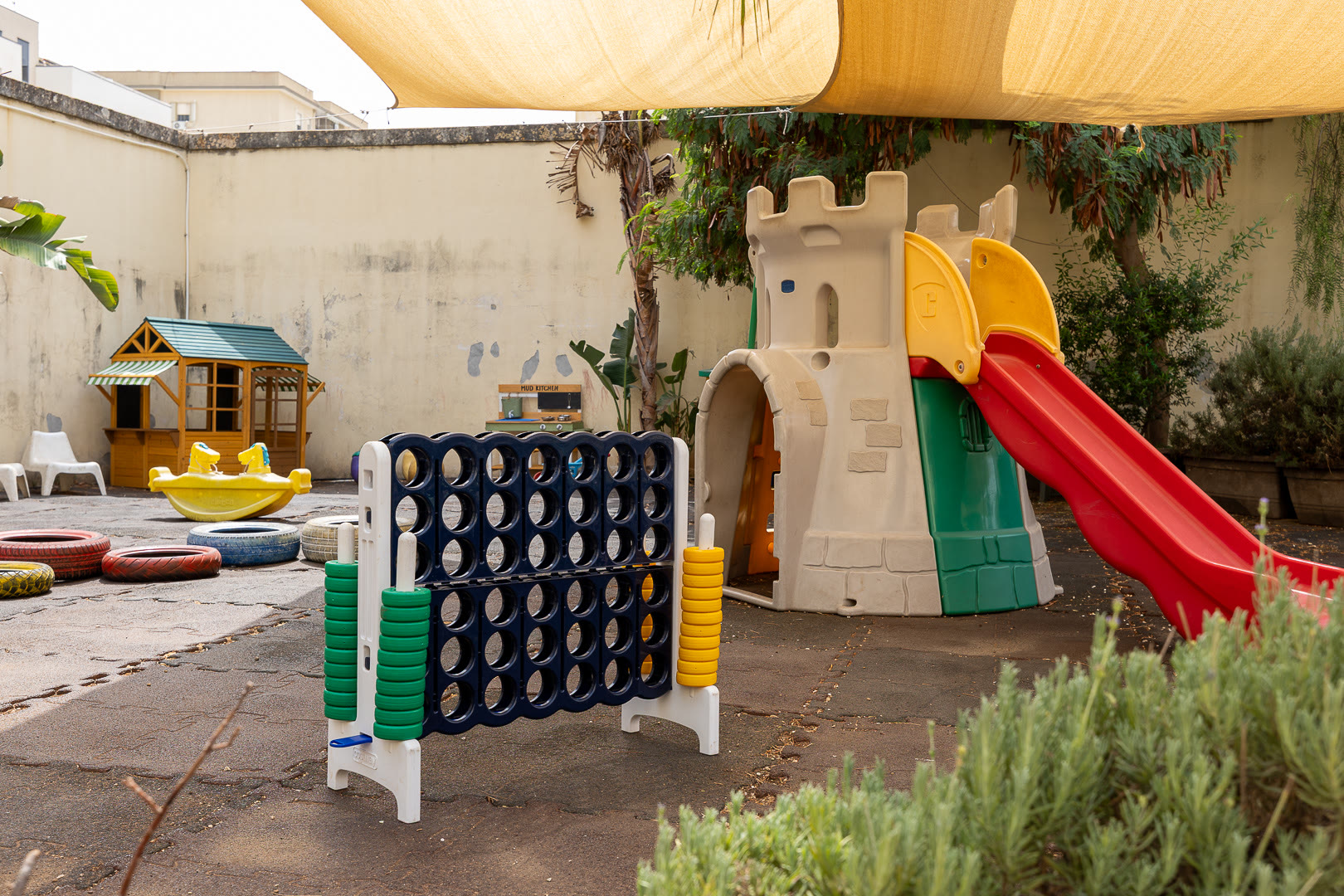 L'area gioco esterna con lo scivolo, la casetta e il castello colorato.
