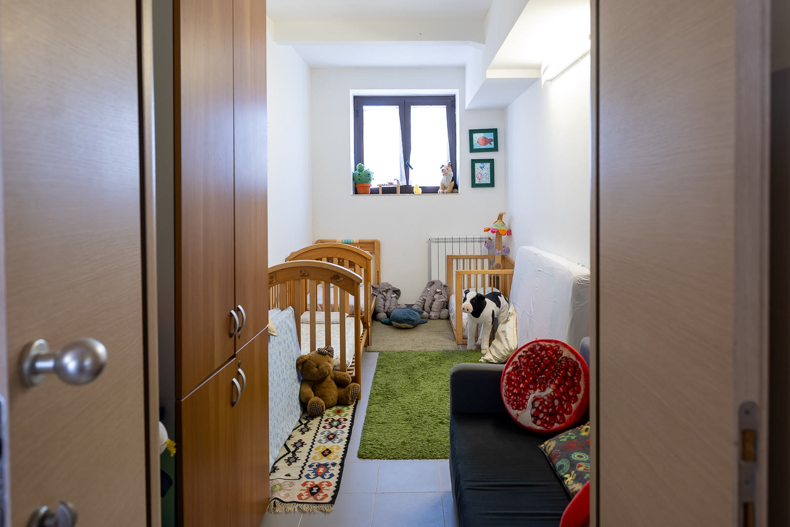 La stanza della nanna del nido, con i lettini in legno e il tappeto verde.