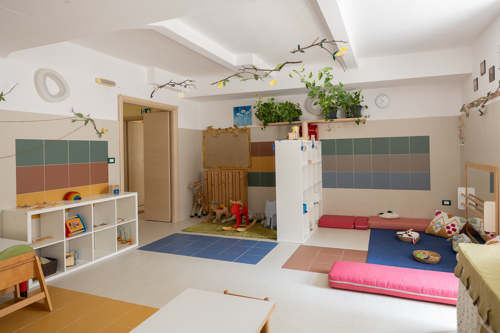 Ambiente del nido: tappeti a terra, parete per arrampicarsi, scaffali bassi con i libri.