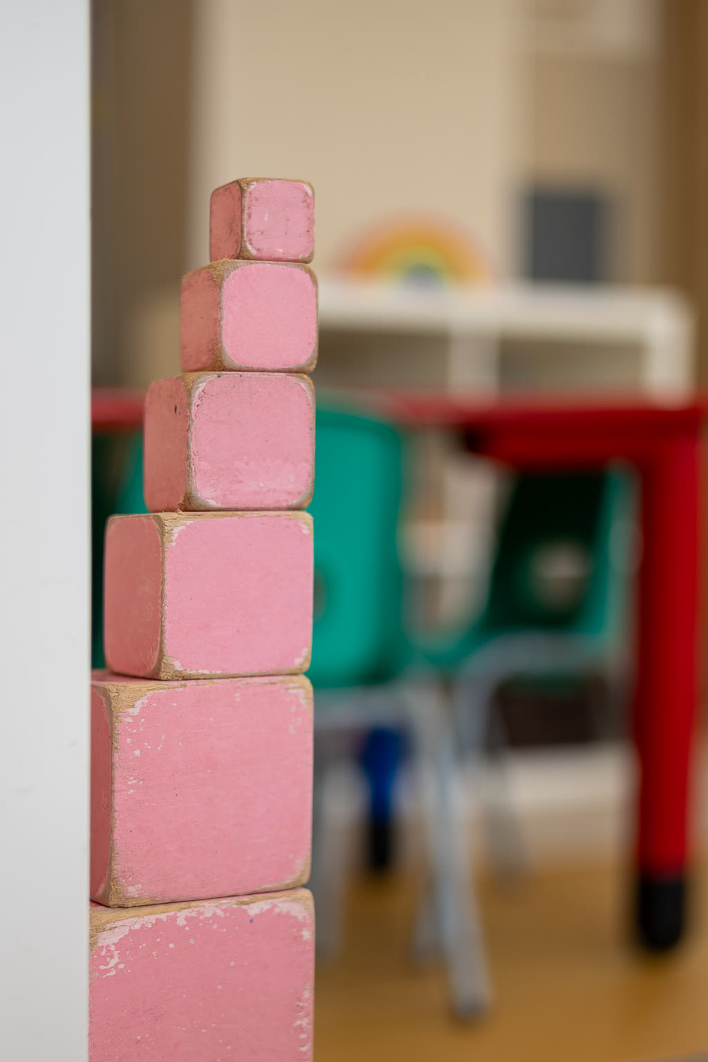 Cubi rosa impilati in ordine di grandezza, sul bordo di un tavolo.