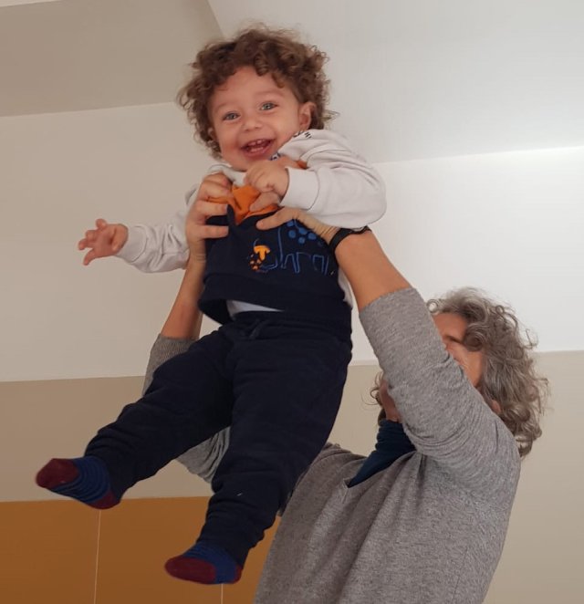 Un'insegnante solleva in alto un bambino che ride.